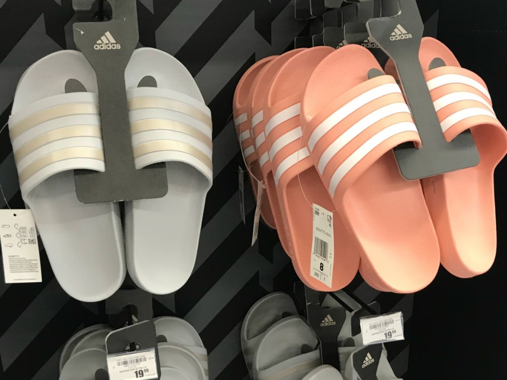 Pink and white Adidas slides hanging on tack at Academy