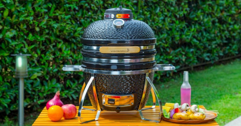 Black Cadet Kamado grill on table surrounded by veggies