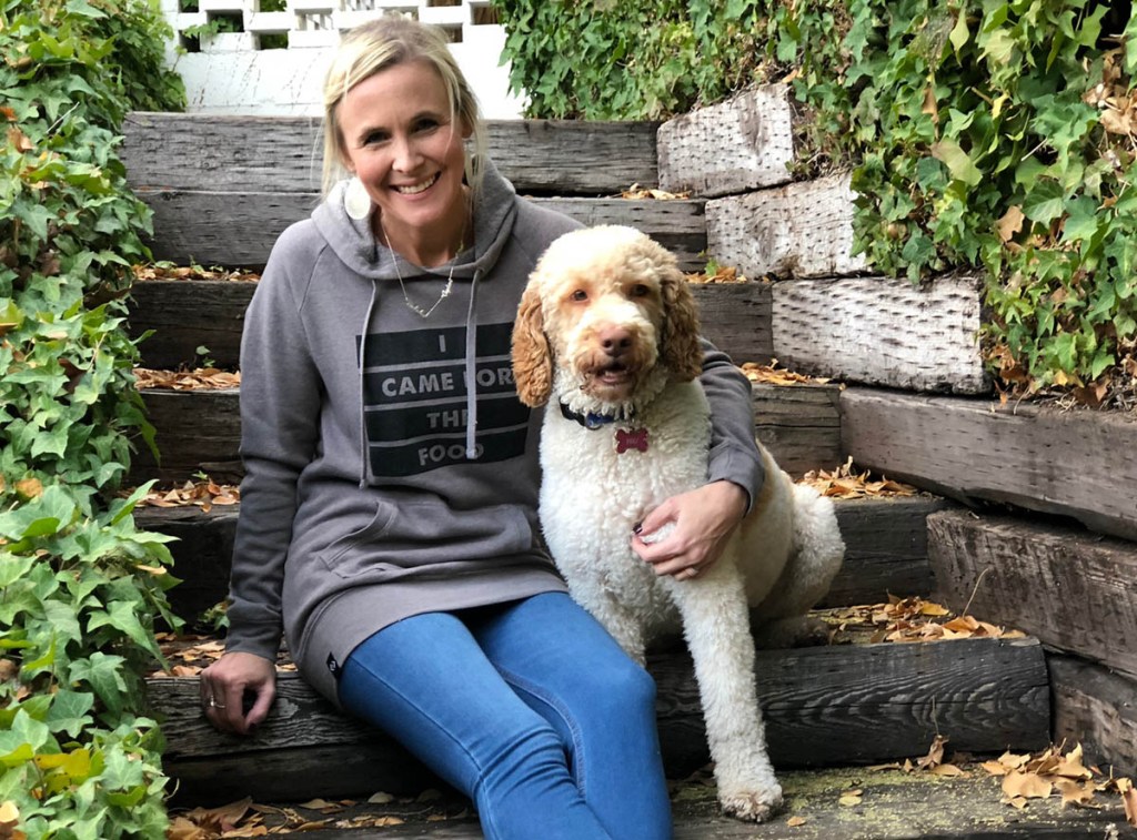 woman with her arm around dog sitting on steps