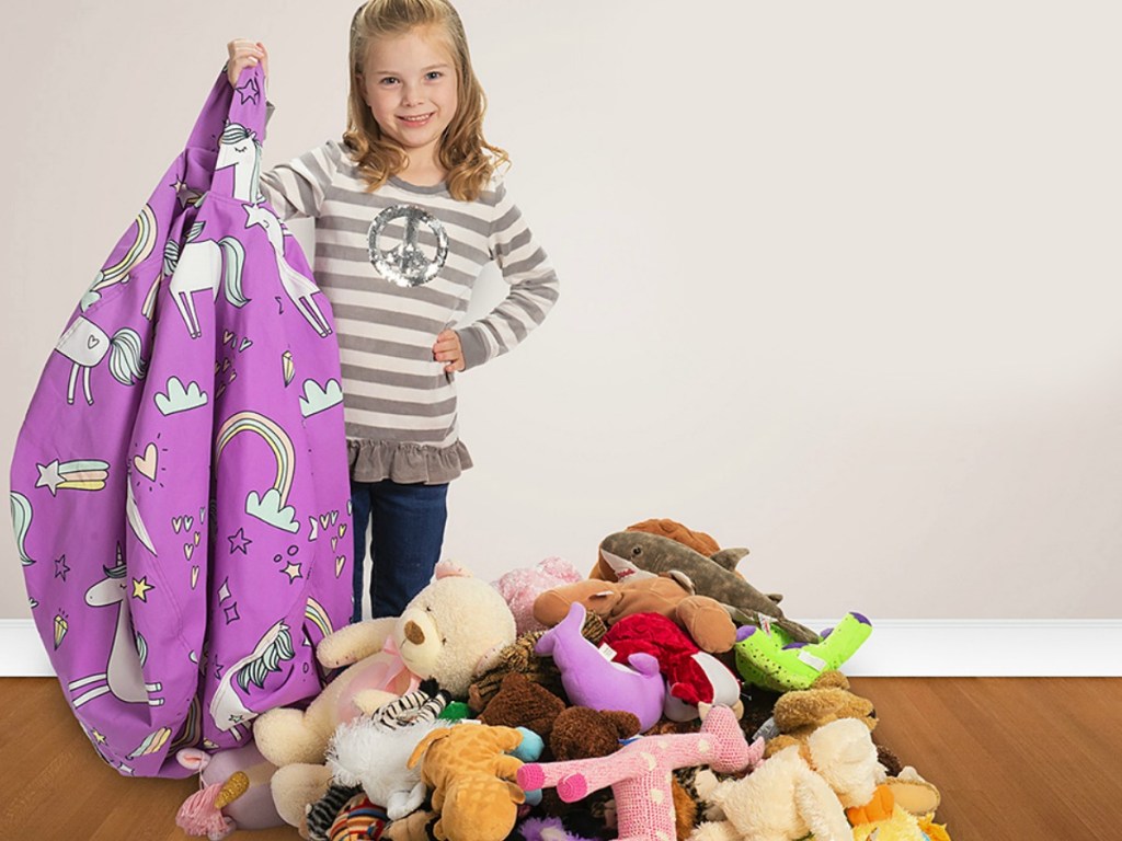 Girl holding empty Creative QT Storage Bean Bag with stuffed animals next to her