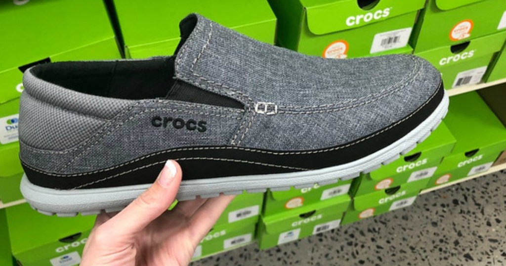 Mens slip on shoes being held in front of a green box