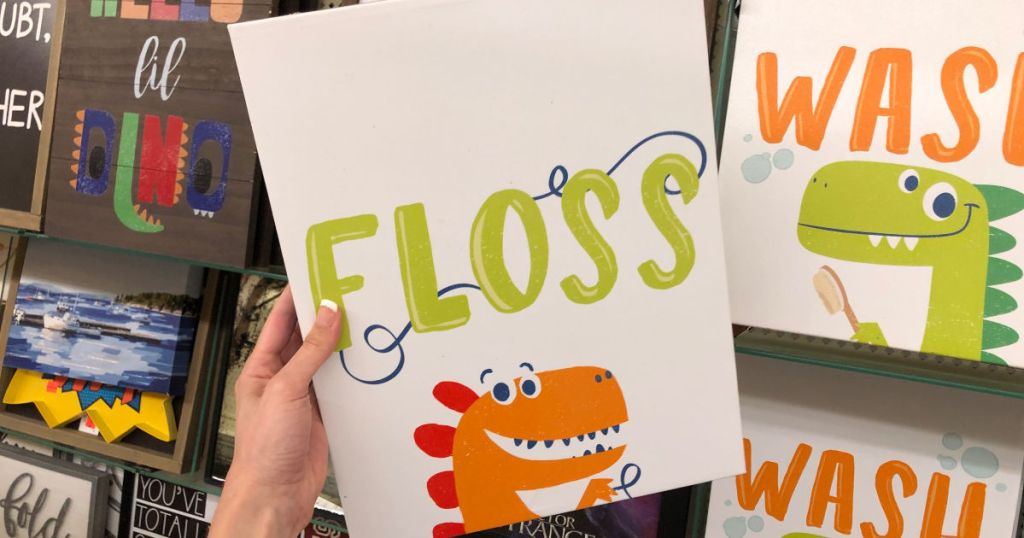 Woman holding Dinosaur Floss Canvas Sign in Hobby Lobby