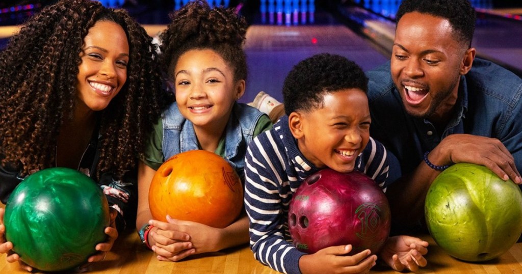 Family laying down at a bowling alley with bowling balls