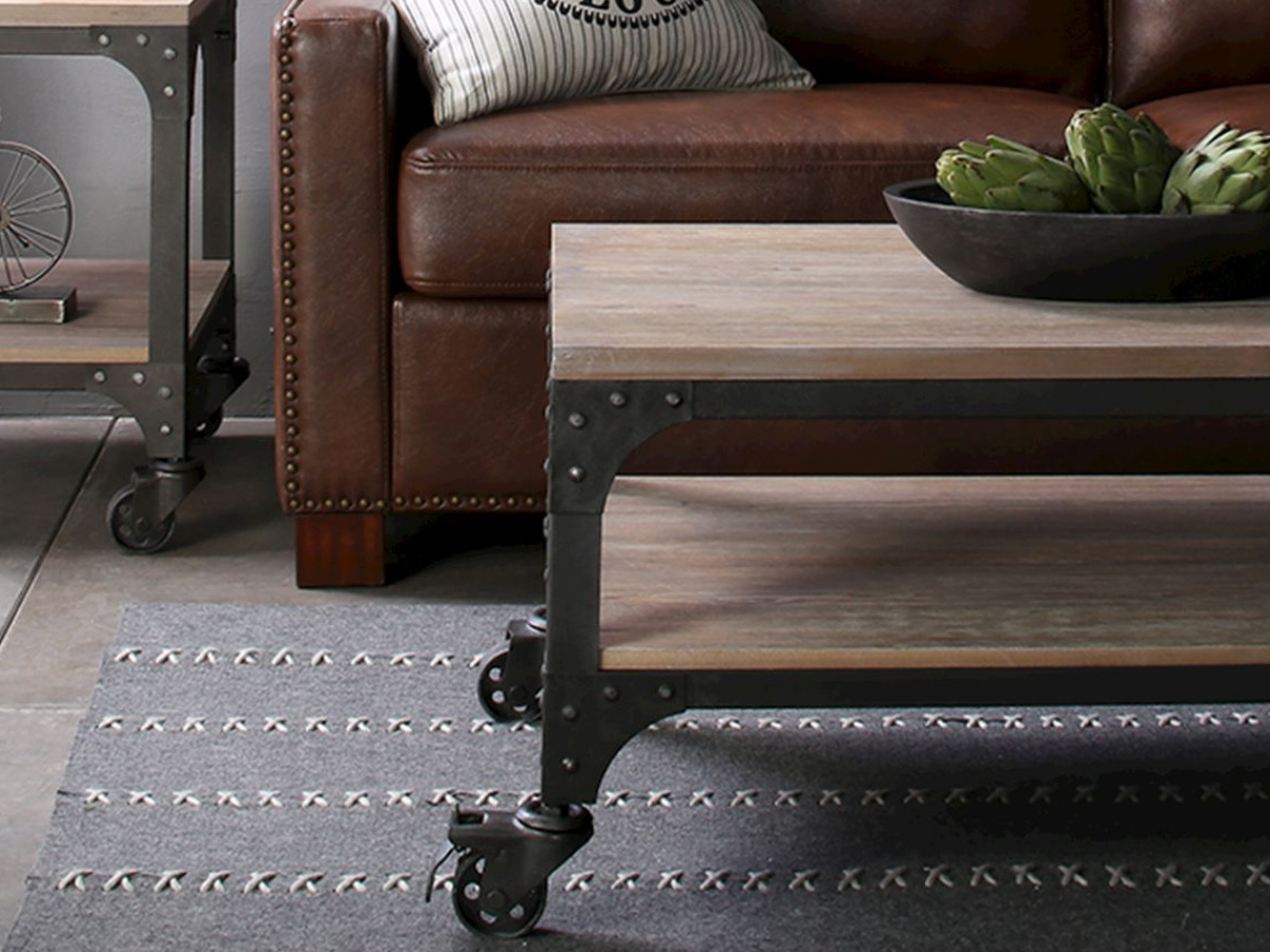 metal and wood coffee table on a rug, in front of a brown couch