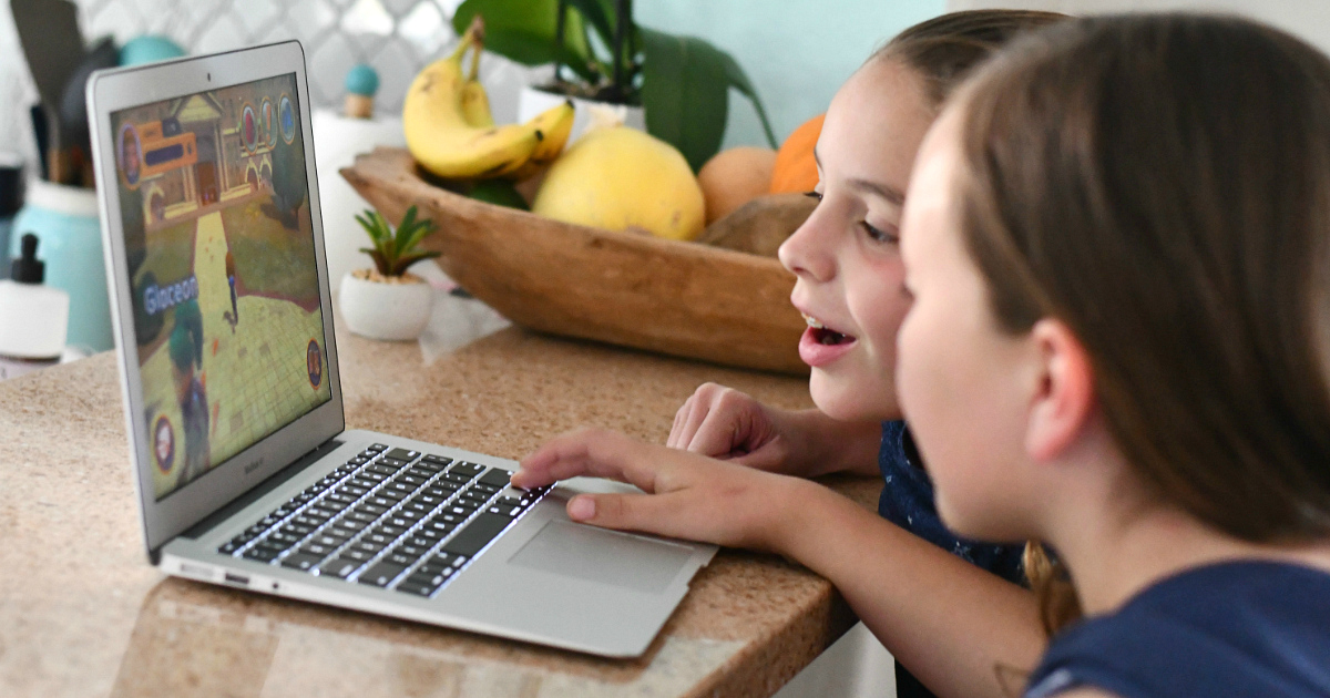 Girls playing Adventure Academy game on laptop