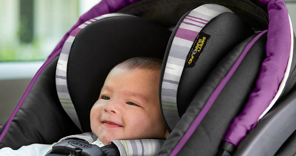 baby sitting in a Graco car seat that is purple with stripes