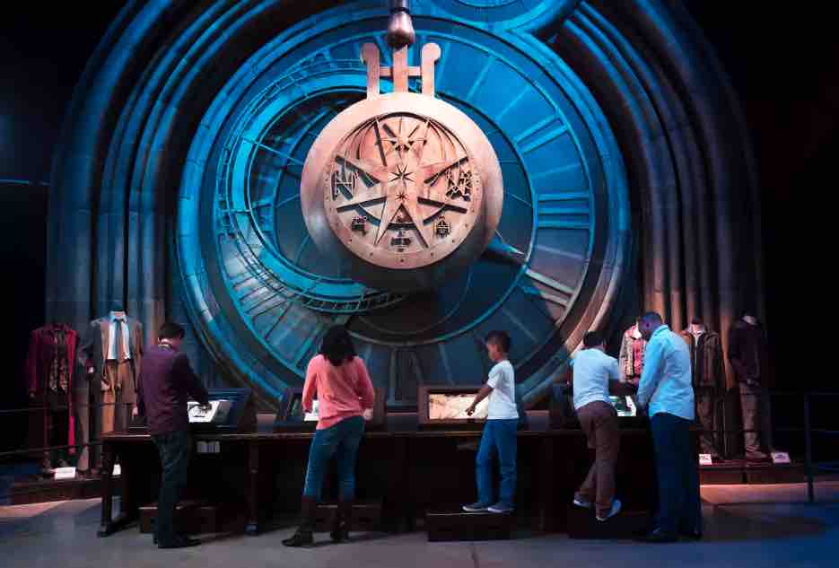 large clock on wall with kids looking at displays