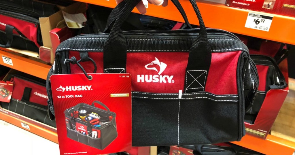 lady holding a 3-Bag Combo of a 15" Tool Tote, 12" Tool Bag, and 20" Duffle bags at home depot