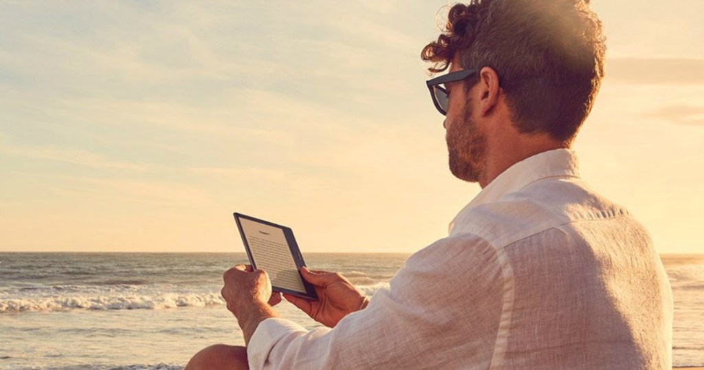 man sitting outside by beach reading ebook