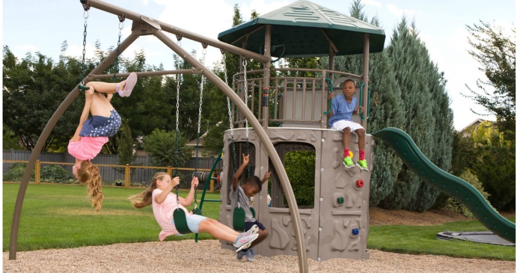 large playset with kids playing on the swings and clubhouse