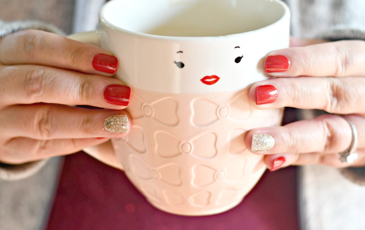 holding a coffee cup with red Impress Nails on 