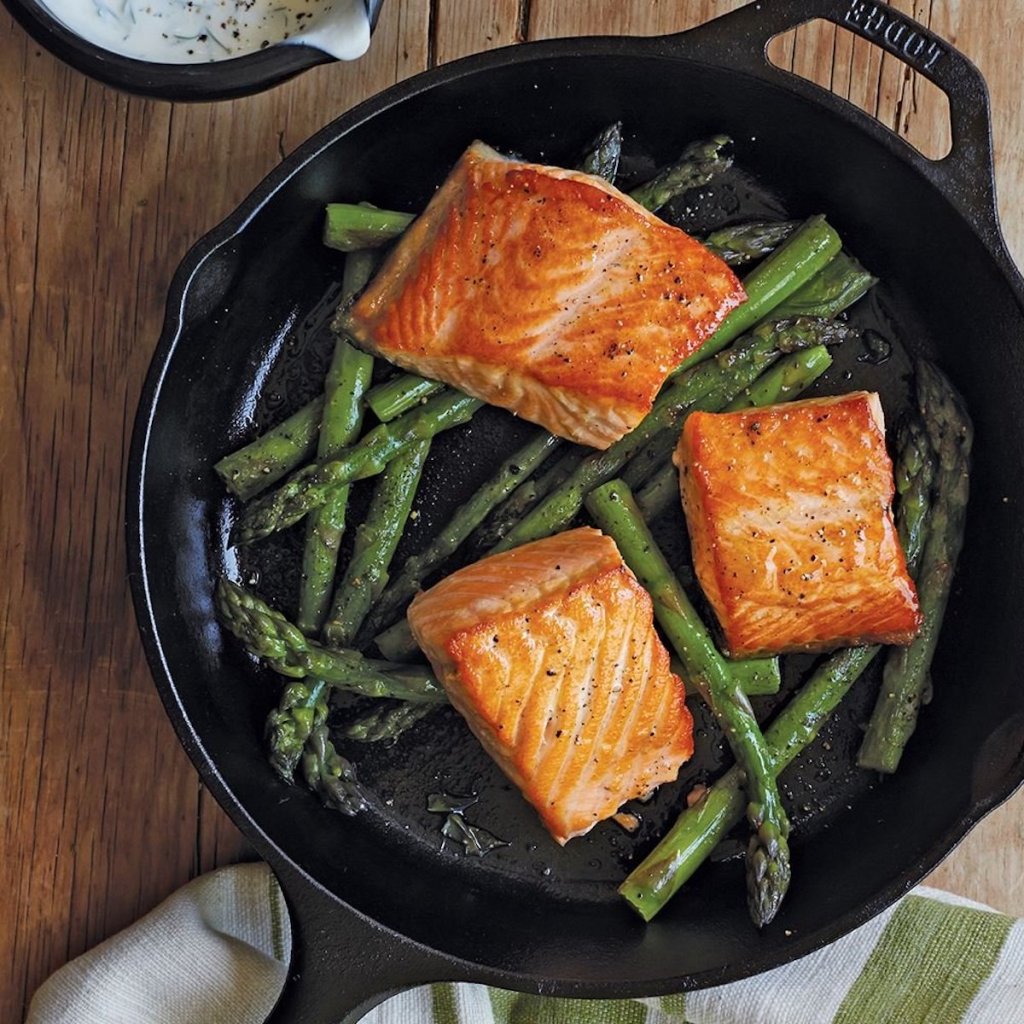 lodge cast iron skillet with salmon and asparagus in the pan