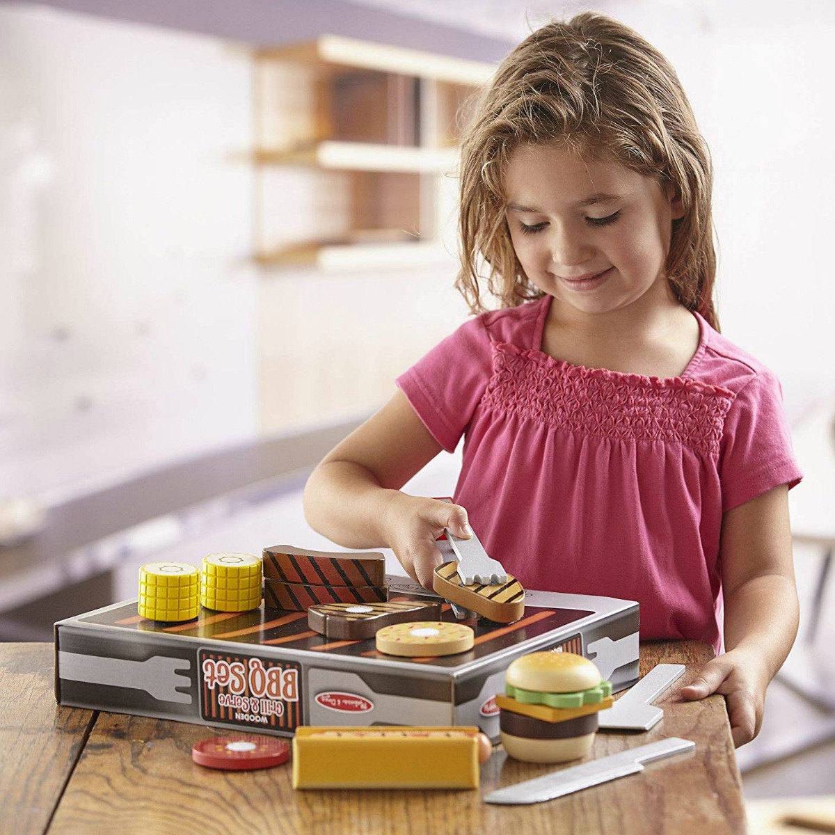 little girl playing with a Melissa & Doug BBQ set at a table