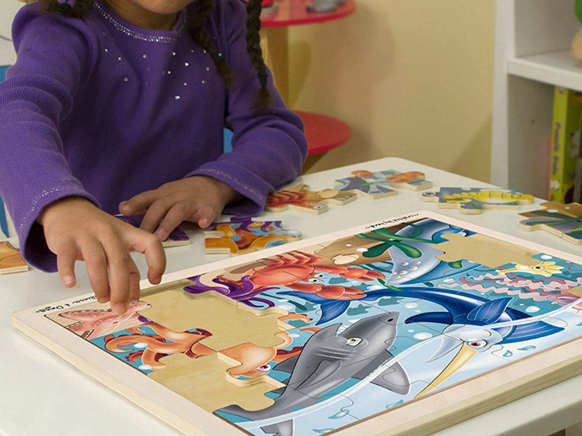 little girl doing a Melissa & Doug sea creature puzzle at a table