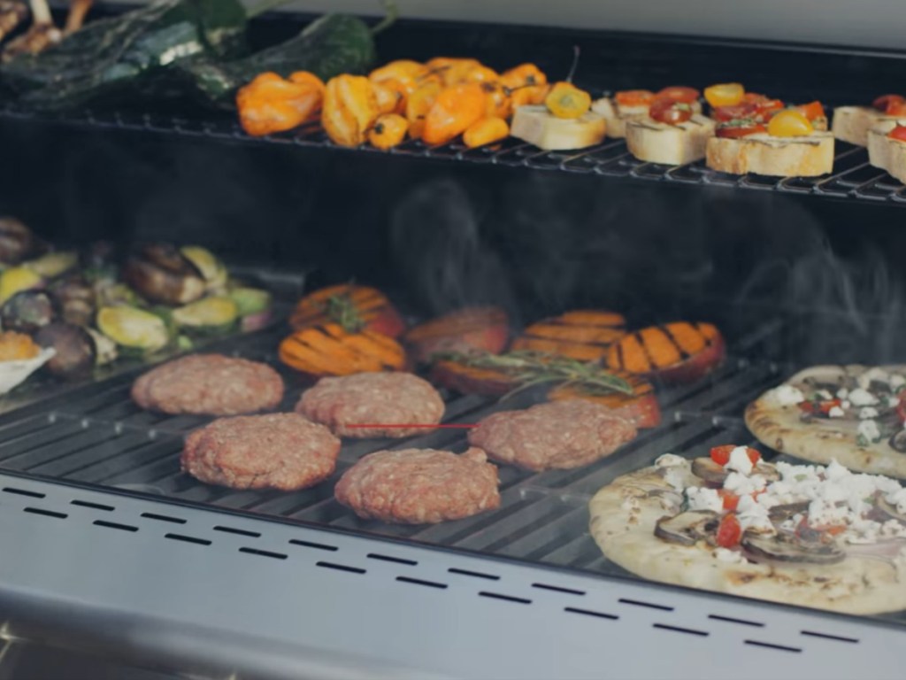 Burgers, pizza, and veggies being grilled on large Nexgrill Deluxe grill