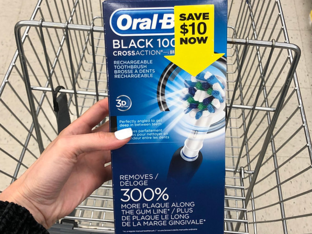 Woman holding Oral-B Pro 1000 rechargeable toothbrush over Walgreens shopping cart