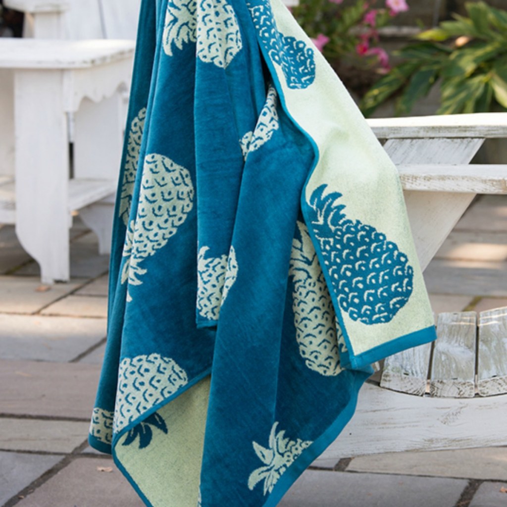 mint and teal pineapple oversized beach towels hanging on a bench