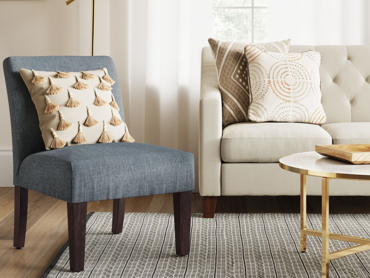 blue fabric and wood chair with throw pillow, next to a couch with pillows