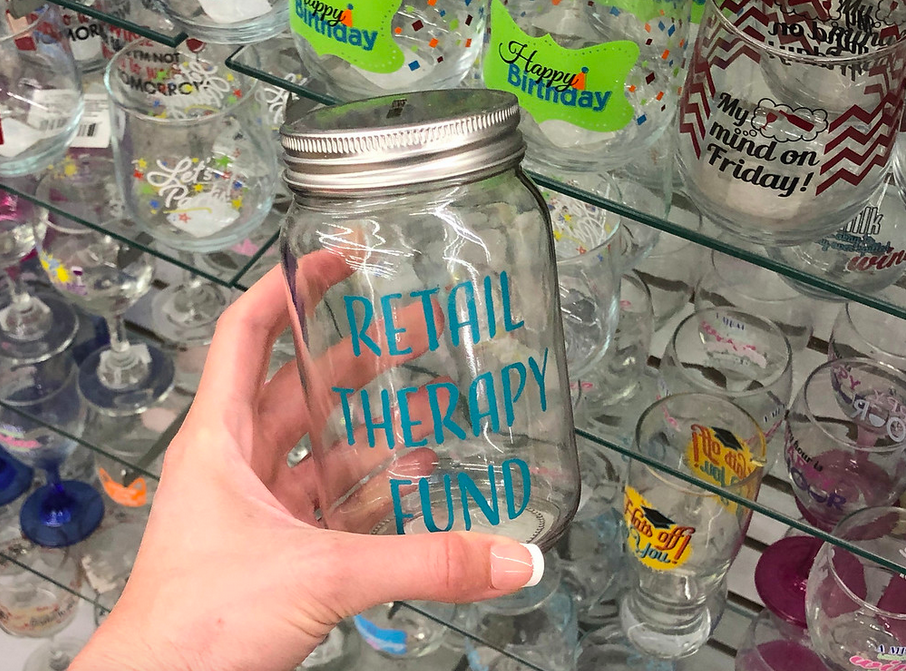 Woman holding Retail Therapy Fund Mason Jar inside Dollar Tree store