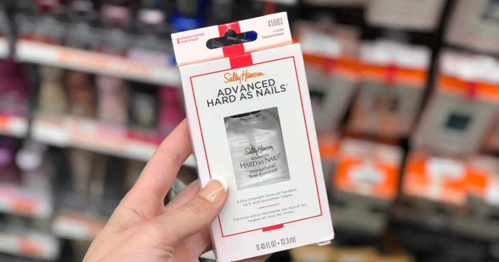 woman hand holding Sally Hansen Advanced Hard as Nails in cvs with product in the background