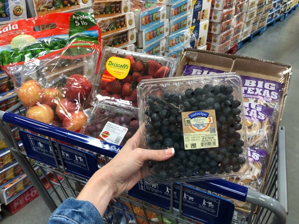 lady holding various grocery items at Sam's club - blueberries and more