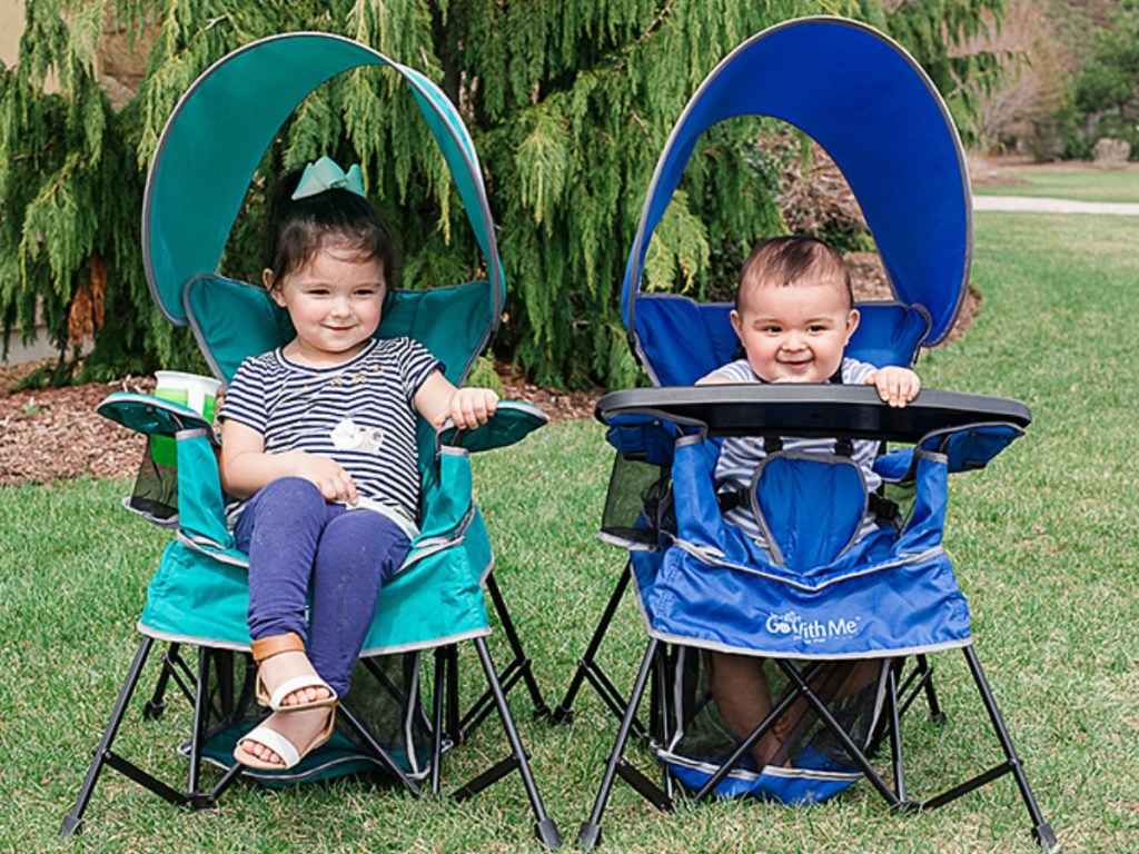 Kids in two portable chairs outside by a tree