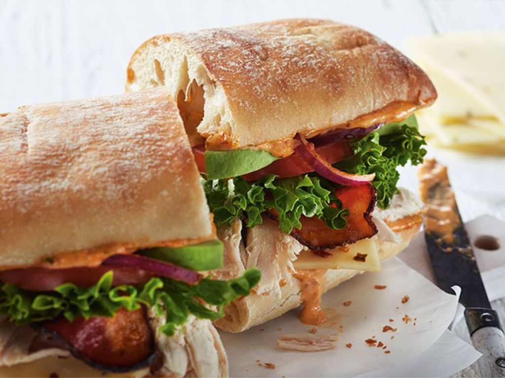 boston market Southwest Chicken BLT on ciabata with knife with chipotle aioli and cheese in background