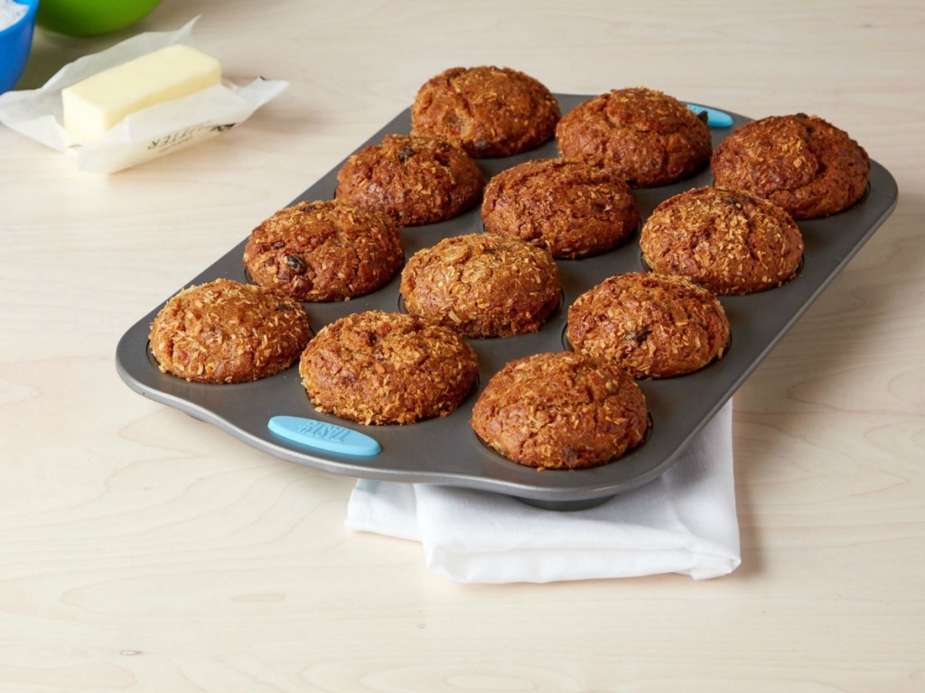 muffin tray with muffins sitting on table with stick of butter beside it