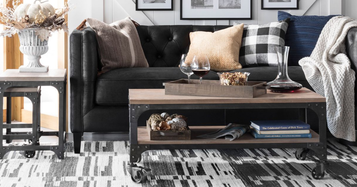 living room scene with a black couch, coffee table, side table, pillows, throws and other decor