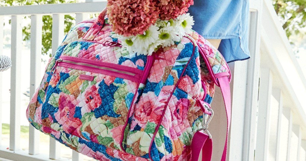 woman holding Vera Bradley weekender bag and flowers