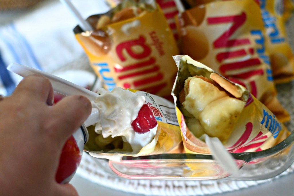 adding whipping cream to bags of walking banana pudding