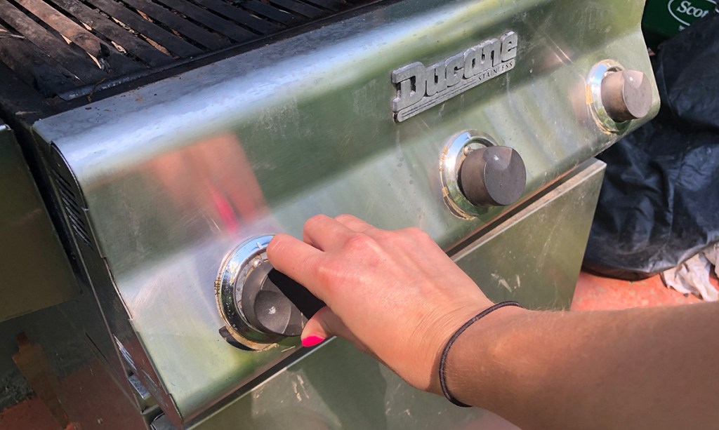 adjusting the dials on a propane grill