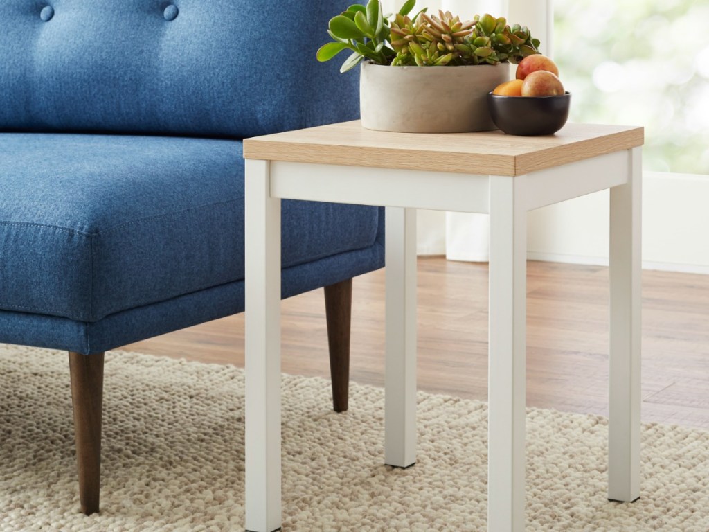 small white table with plants and apples on it next to a couch