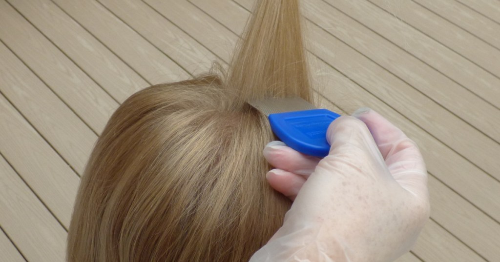 girl with blonde hair and gloved hand holding blue lice comb