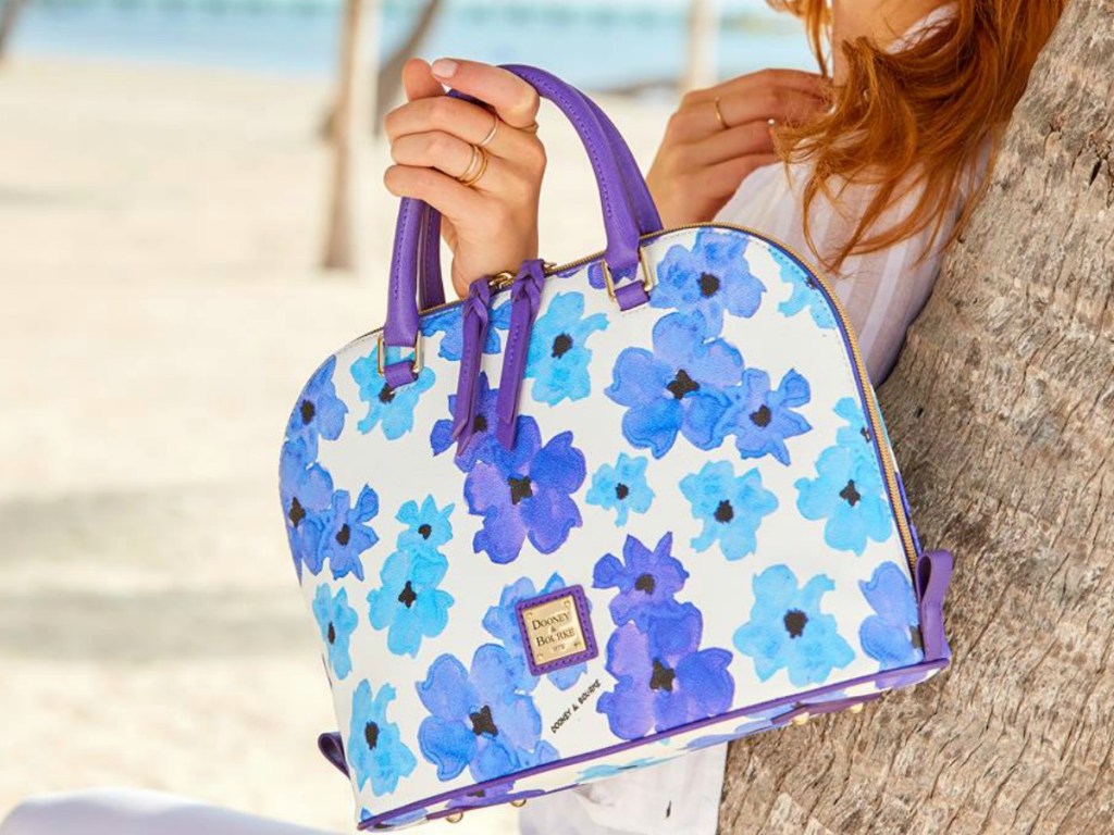 woman holding floral purse on the beach