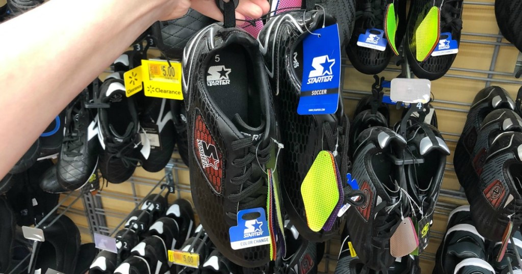 hand holding up pair of shoes by store display