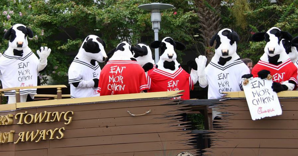 people in cow costumes with eat mor chikin jerseys standing on a parade float