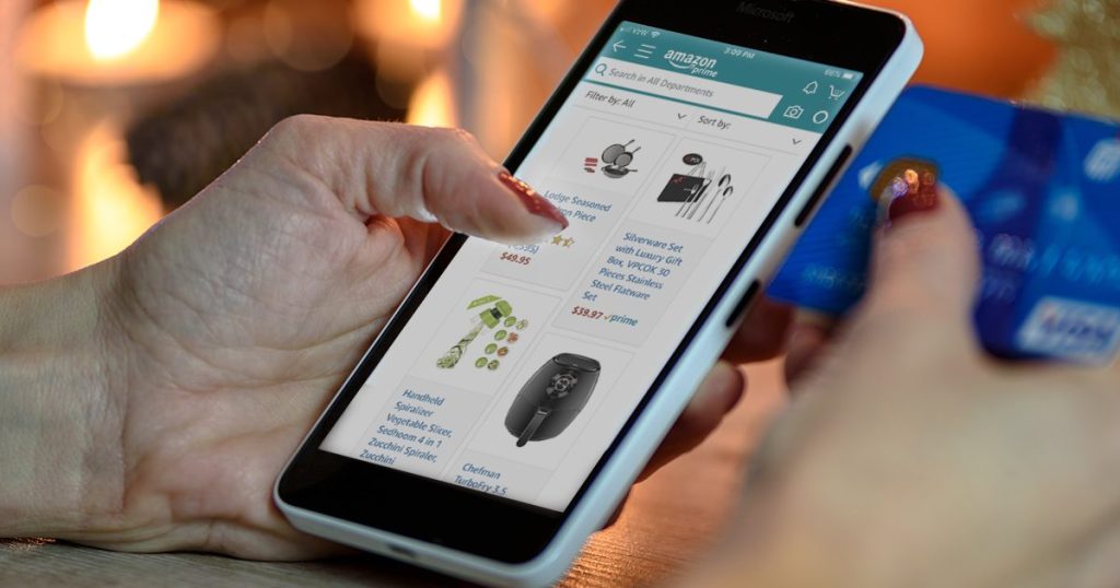 scrolling amazon on phone with credit card in hand