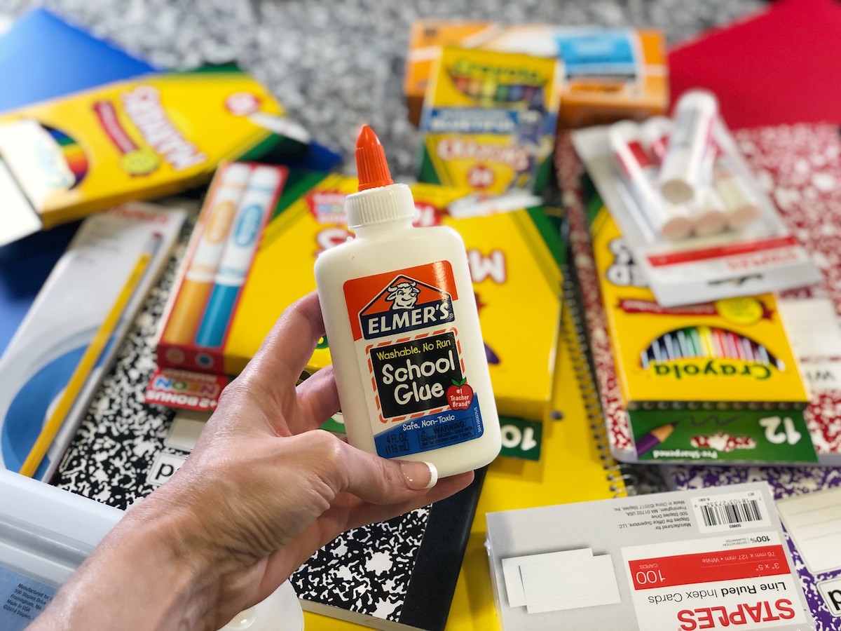 Elmer's Glue held above pile of school supplies