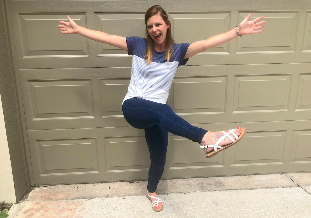 woman standing in front of garage door with color block shirt and jeans on