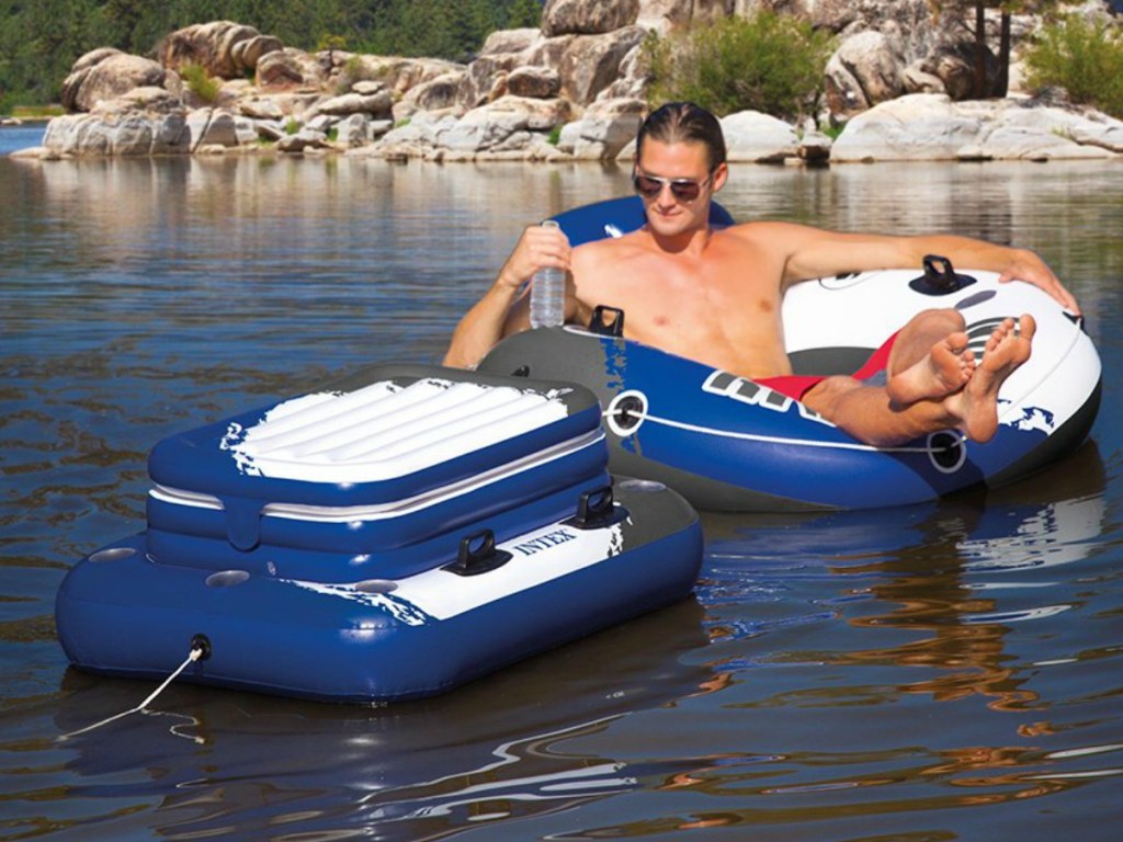 man on tube with cooler next to him floating on river
