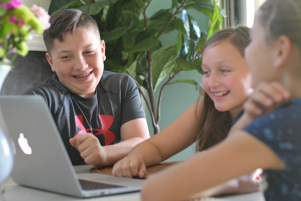 kids laughing while looking at laptop