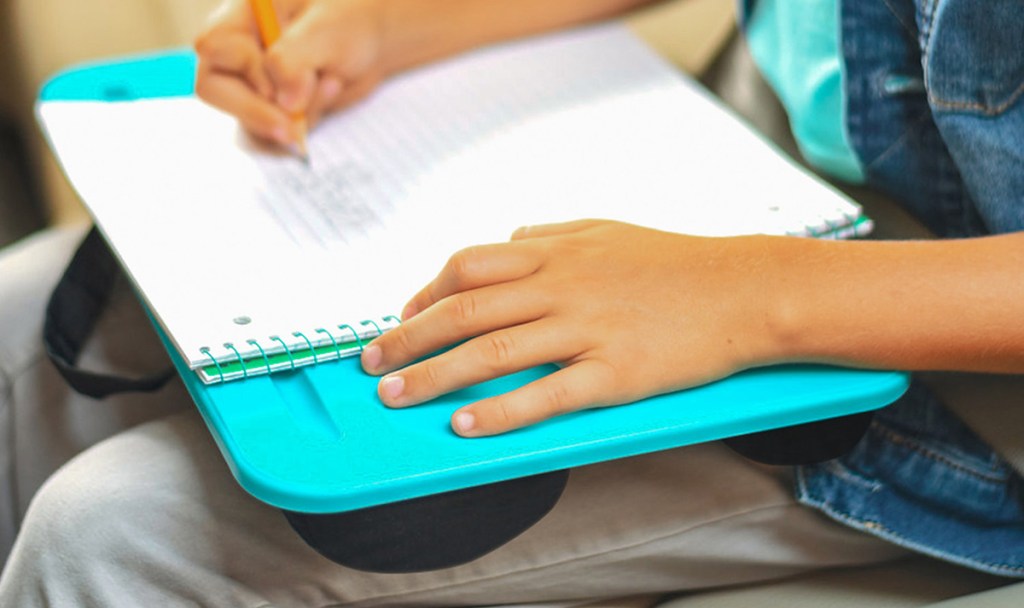 writing in notebook on top of lap desk