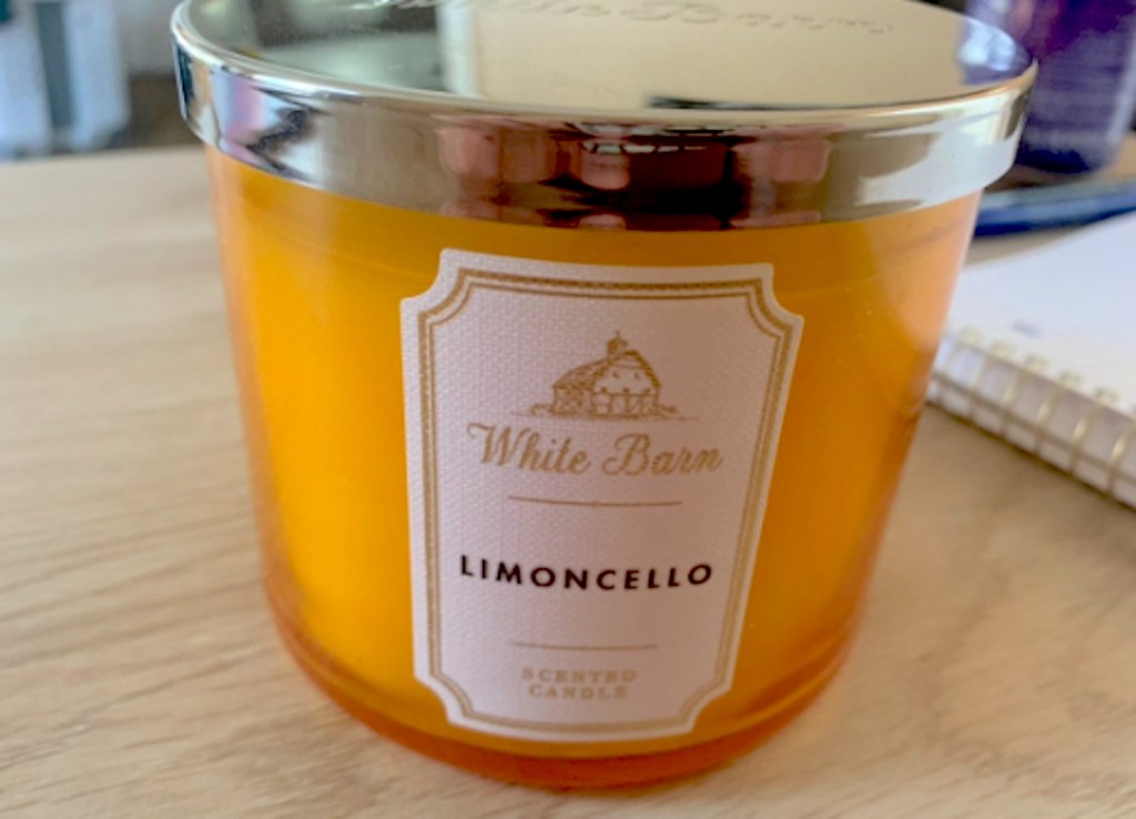 orange limoncello candle with silver lid sitting on wood table
