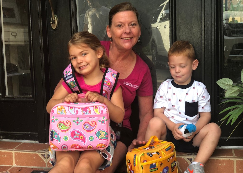 grandma with boy and girl with lunchboxes