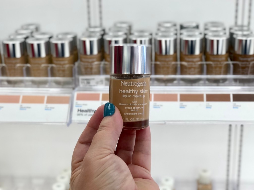 womans hand holding neutrogena healthy skin liquid makeup in front of display of neutrogena make up at target