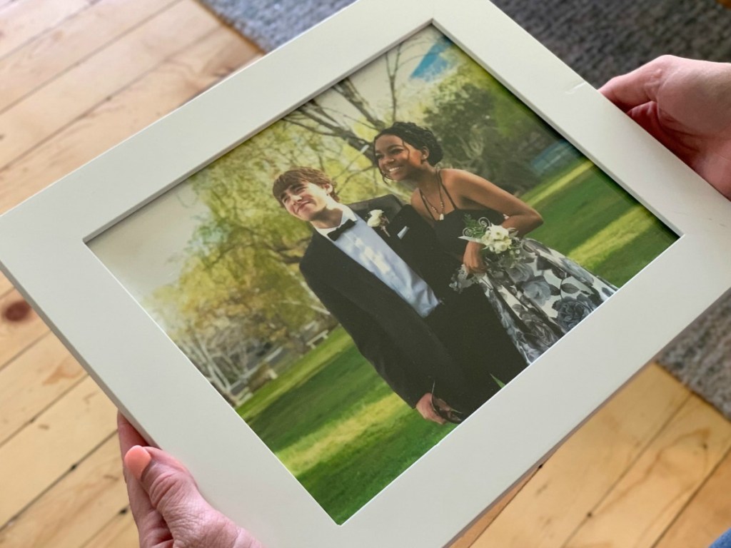 someone holding framed picture of boy and girl in prom attire