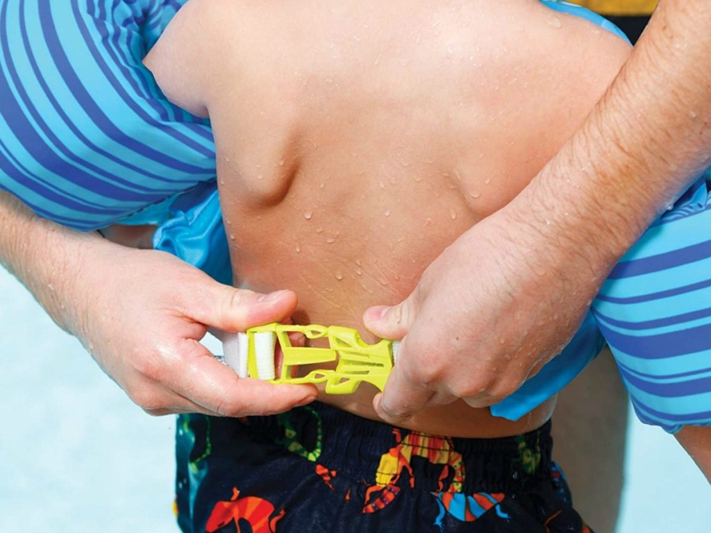 man buckling puddle jumper to child in the pool