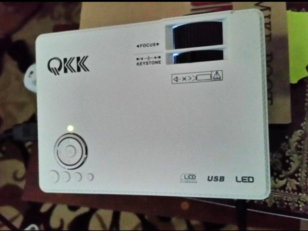 qkk mini projector on table with maroon rug