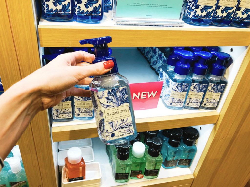 hand holding sea island cotton hand soap with soaps in the background on shelf